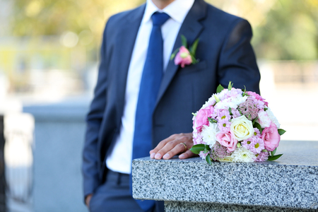 Groom holding wedding bouquet outdoorsの写真素材
