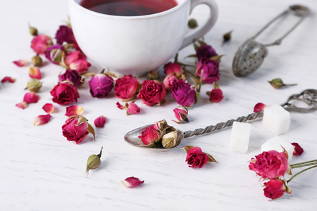 Tea and tea rose flowers on table closeupの写真素材