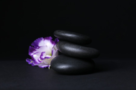 Balanced pebbles with beautiful flower on dark grey backgroundの写真素材