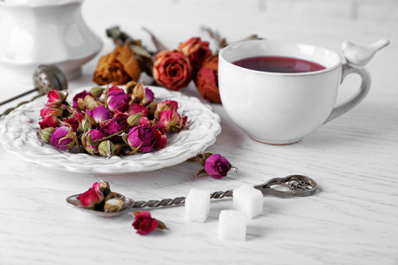 Tea and tea rose flowers on table closeupの写真素材