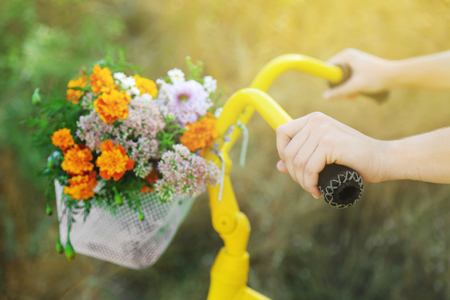 Beautiful yellow bicycle with bouquet of flowers in basket, outdoorsの写真素材