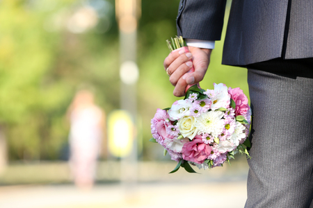 Groom holding wedding bouquet outdoorsの写真素材