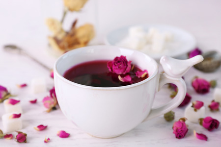 Tea and tea rose flowers on table closeupの写真素材