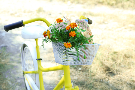 Beautiful yellow bicycle with bouquet of flowers, milk bottle and bread in basket, outdoorsの写真素材