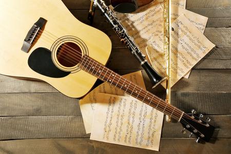 Acoustic guitar, soprano saxophone, violin, flute and note sheets on wooden backgroundの写真素材