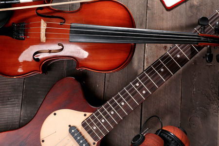 Electric guitar, violin, and headphones on wooden backgroundの写真素材