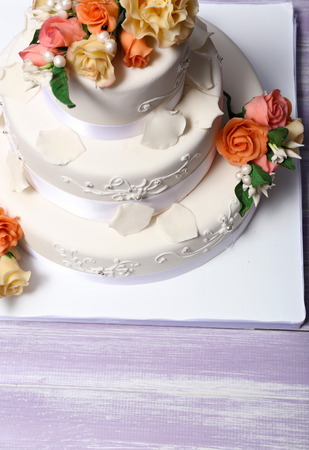 White wedding cake decorated with flowers on wooden table, close upの写真素材