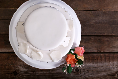 White wedding cake decorated with flowers on wooden backgroundの写真素材
