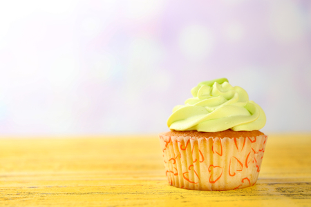 Tasty cupcake on yellow wooden table against unfocused backgroundの写真素材
