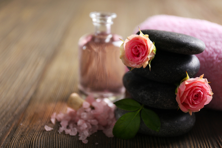 Spa composition of a towel, salt, flowers and stones, on wooden backgroundの写真素材