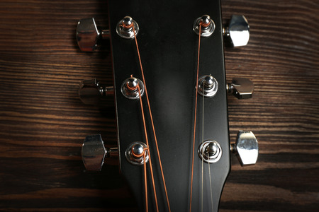 Close up of acoustic guitar neck on wooden background