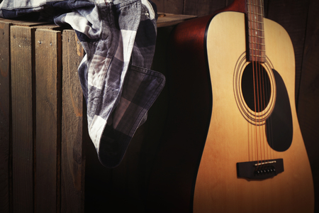 Guitar and shirt left on crate on wooden wall backgroundの写真素材
