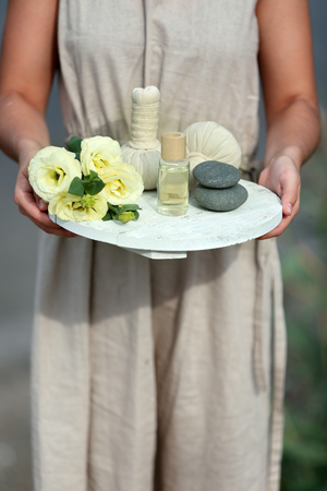 Female hands with tray of spa products, outdoorsの写真素材