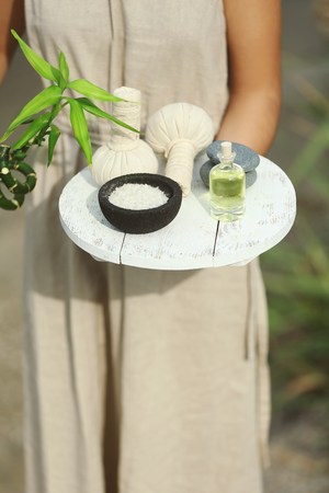 Female hands with tray of spa products, outdoorsの写真素材