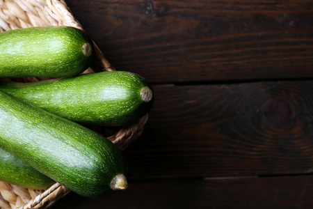 Fresh zucchini in wicker basket on wooden backgroundの写真素材