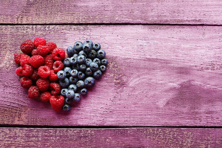 Heart shaped raspberries and blueberries on old wooden backgroundの写真素材