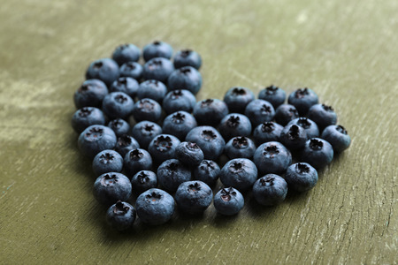 Heart shaped bilberries on old wooden backgroundの写真素材