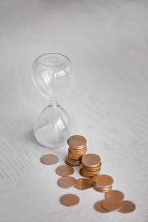 Hourglass with coins on table close-upの写真素材