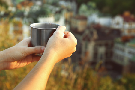 Metal touristic tea cup in female handsの写真素材