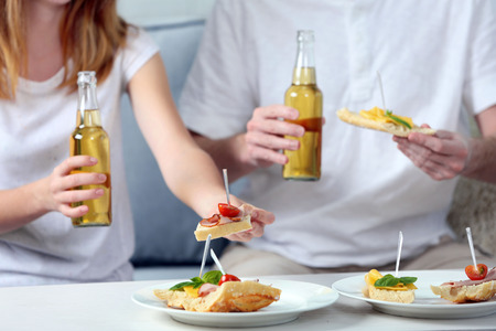 Friends hands with bottles of beer and snacks , close upの写真素材