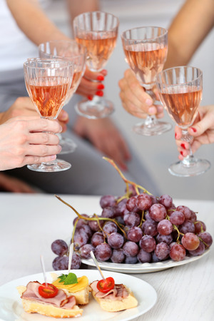Friends hands with glasses of wine and snacks, close upの写真素材