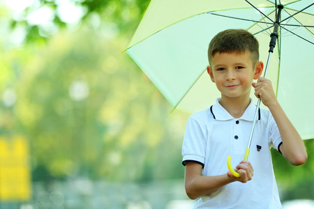 Boy under big creamy umbrella at the parkの写真素材