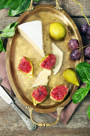 Ripe figs and cheese on tray, on wooden backgroundの写真素材