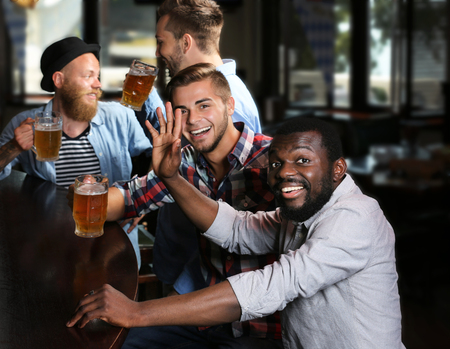 Happy friends having fun and drinking beer in pubの写真素材