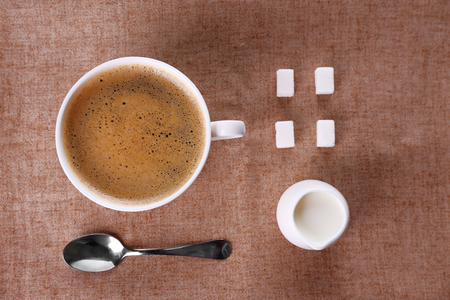 Cup of coffee with cream and sugar on sackclothの写真素材