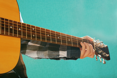 Guitars neck in musician hands on blue background, close upの写真素材