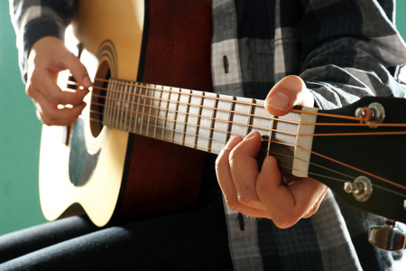 Musician plays guitar on blue background, close up