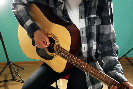 Musician plays guitar on blue background, close up