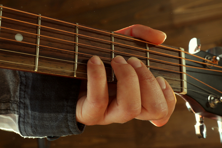 Guitars neck in guitarist hands on wooden background, close upの写真素材