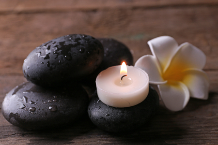Relaxing concept - fragipani flower, pebbles and candles on wooden backgroundの写真素材