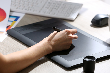 Female hand drawing on the graphic tablet in the office, close-upの写真素材