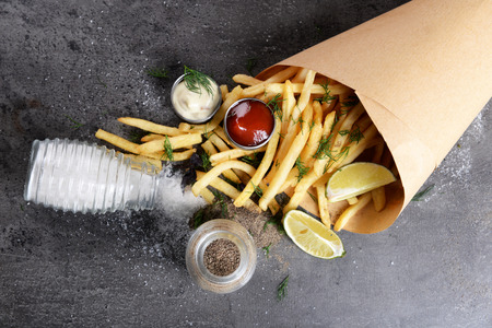 French fries in bag with sauce, lime and spice on tableの写真素材
