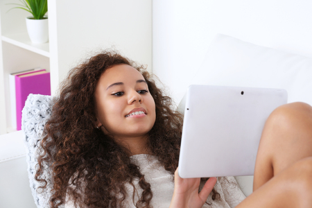 Pretty woman on sofa using  white tabletの写真素材