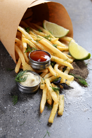 French fries in bag with sauce, lime and spice on tableの写真素材