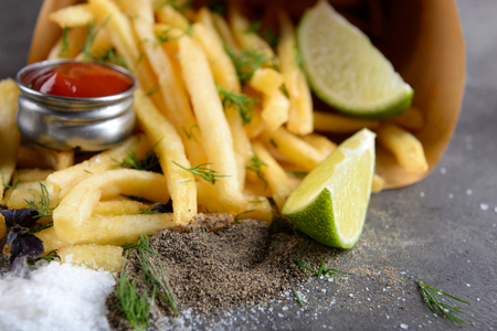 French fries in bag with sauce, lime and spice on tableの写真素材