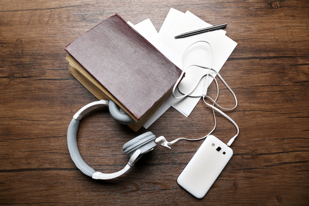 Headphones with old book and smartphone on wooden tableの写真素材