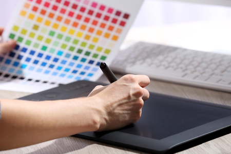 Female hand drawing on the graphic tablet in the office, close-upの写真素材