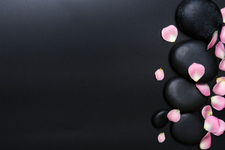 Spa stones and flower petals on black backgroundの写真素材