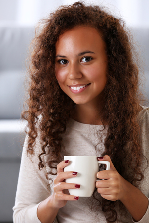 Close up portrait of pretty young woman drinking coffee on white backgroundの写真素材