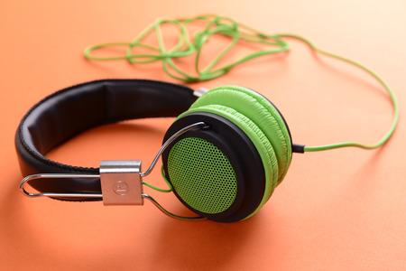A pair of green-black headphones, on orange backgroundの写真素材