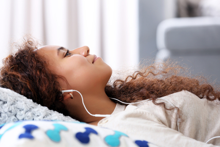 Close up portrait of listening music pretty girl who resting on  the floorの写真素材