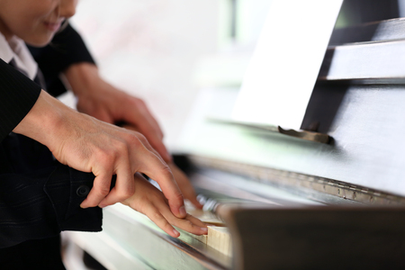 Musician teacher trains to play piano little girl, close upの写真素材