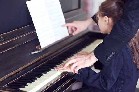 Musician teacher trains to play piano little girl, close upの写真素材