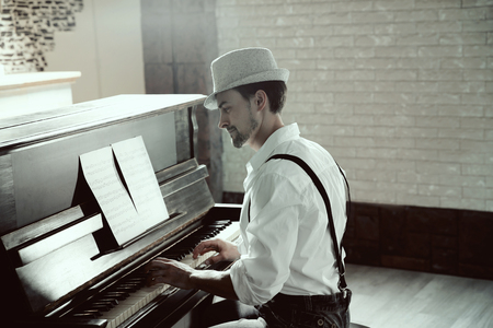 Handsome young man in hat making piano musicの写真素材