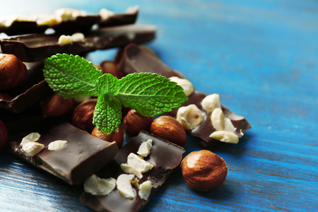 Chocolate pieces with nuts on color wooden backgroundの写真素材