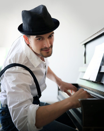 Handsome young man in hat making piano musicの写真素材